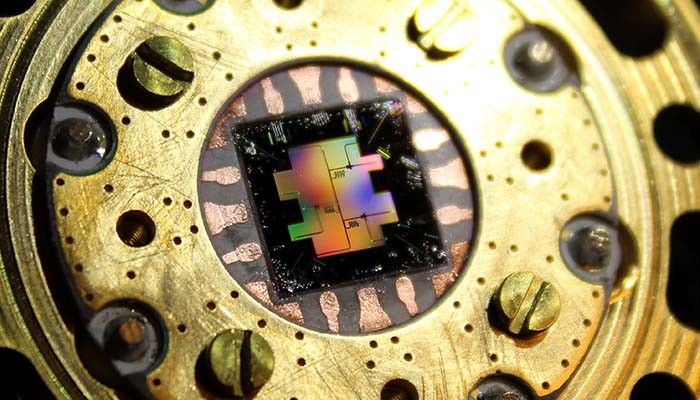 Photo of the centimeter-sized silicon chip which has three separate superconducting quantum bits