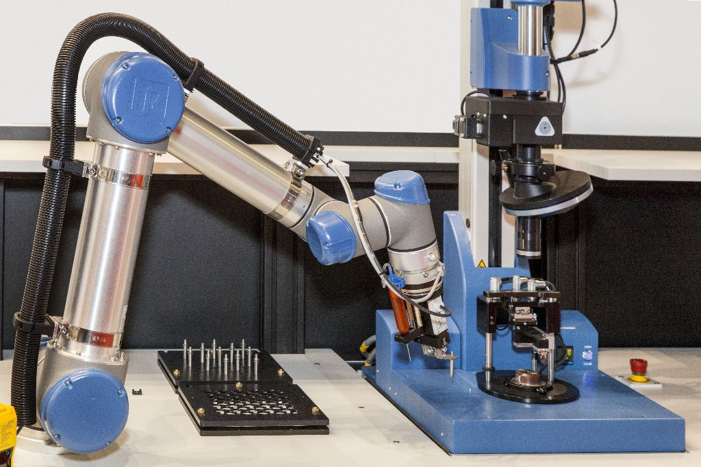 A robot loads the OptiCentric® 100 first with an arbor and then with a microlens. Both are aligned and cemented by the OptiCentric® 100.