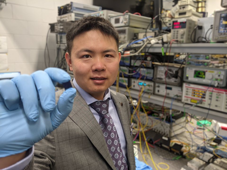 Dr Xingyuan Xu with the integrated optical microcomb chip, which forms the core part of the optical neuromorphic processor.
