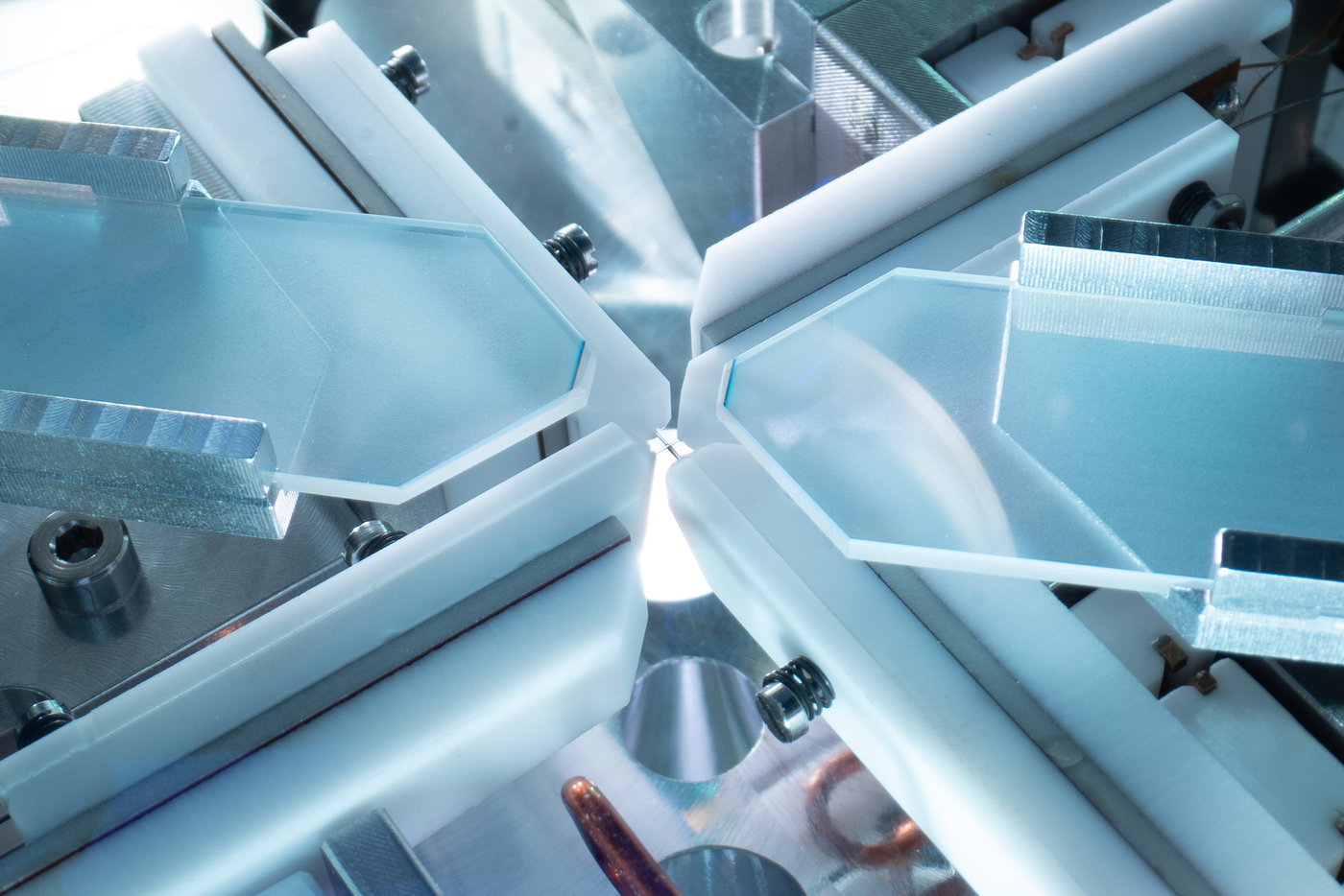 Inside a vacuum chamber, physicists of the Max Planck Institute of Quantum Optics trap a single atom with two crossing optical resonators. They are each made of two optical fibres which are visible in the crossing point. This setup enables a destruction-free detection of photonic qubits.