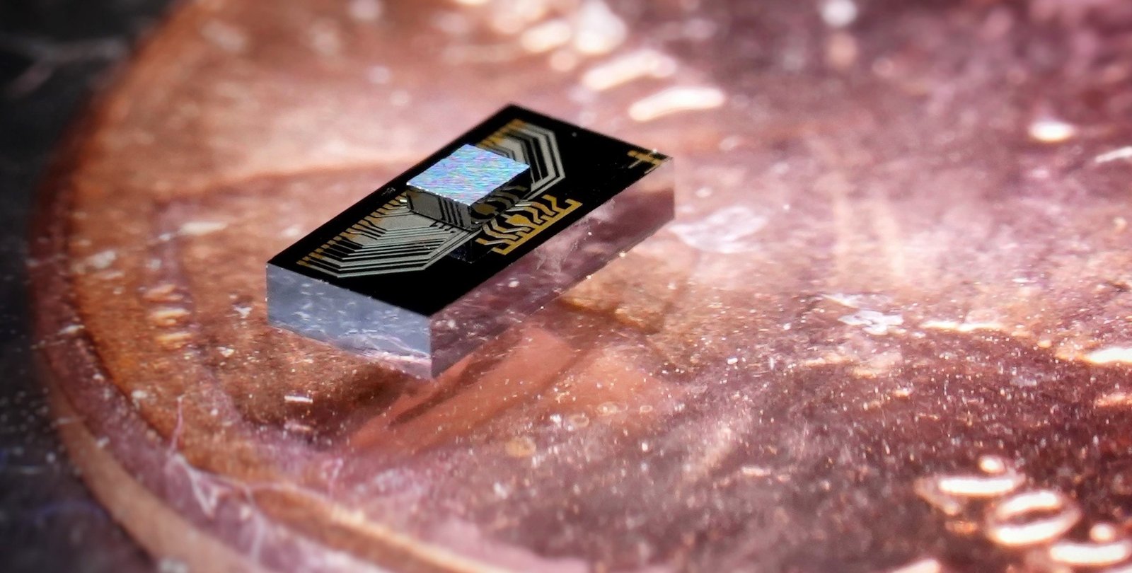 The chip sandwich: an electronics chip integrated with a photonics chip, sitting atop a penny for scale.