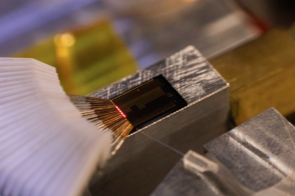 Laser light glows on the surface of a photonics chip.