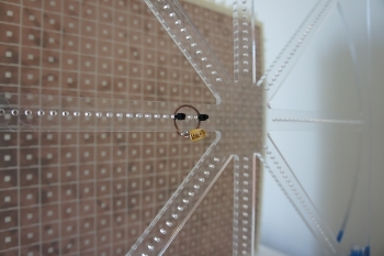 This small copper coil and its twin were used in the experiment to send and receive power using electromagnetic fields. In the background is the metamaterial “superlens” that dramatically increased the power transfer’s range. Credit courtesy of Guy Lipworth and Joshua Ensworth, graduate student researchers at Duke University