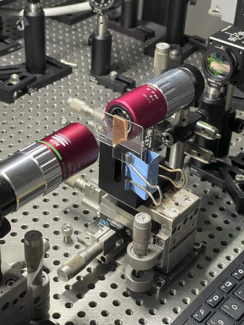 Close-up revealing how two red lens modules align with a glass plate, carefully tuning the path of the laser