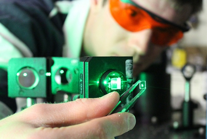 Los Alamos postdoctoral fellow William Rice holds a crystal of strontium titanate up to the light