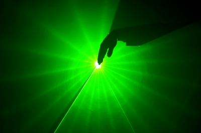 a hand in a green light lighted from a laser effect show