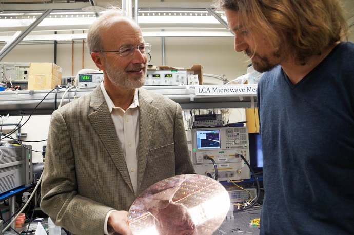 John Bowers and postdoctoral researcher Tin Komljenovic with a wafer of integrated photonic circuitry to be manufactured by AIM