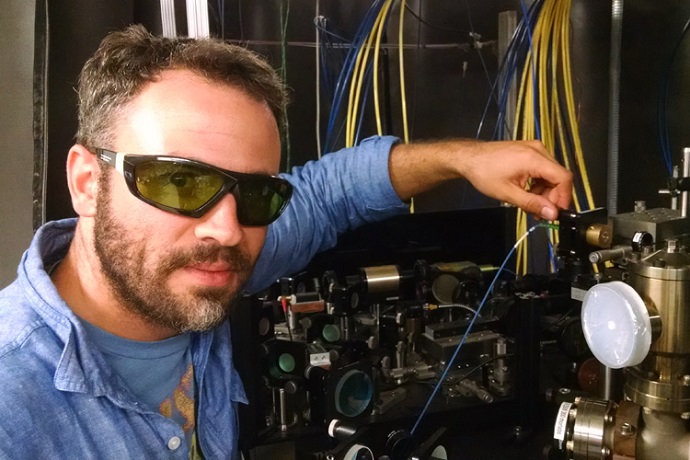 Ryan Olf dons protective glasses to adjust the lasers and vacuum chambers required to trap and cool Bose-Einstein Condensates