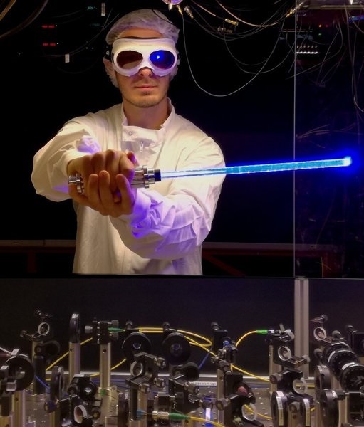PhD candidate Nicolas Tolazzi holding a toy light saber in front of the experiment
