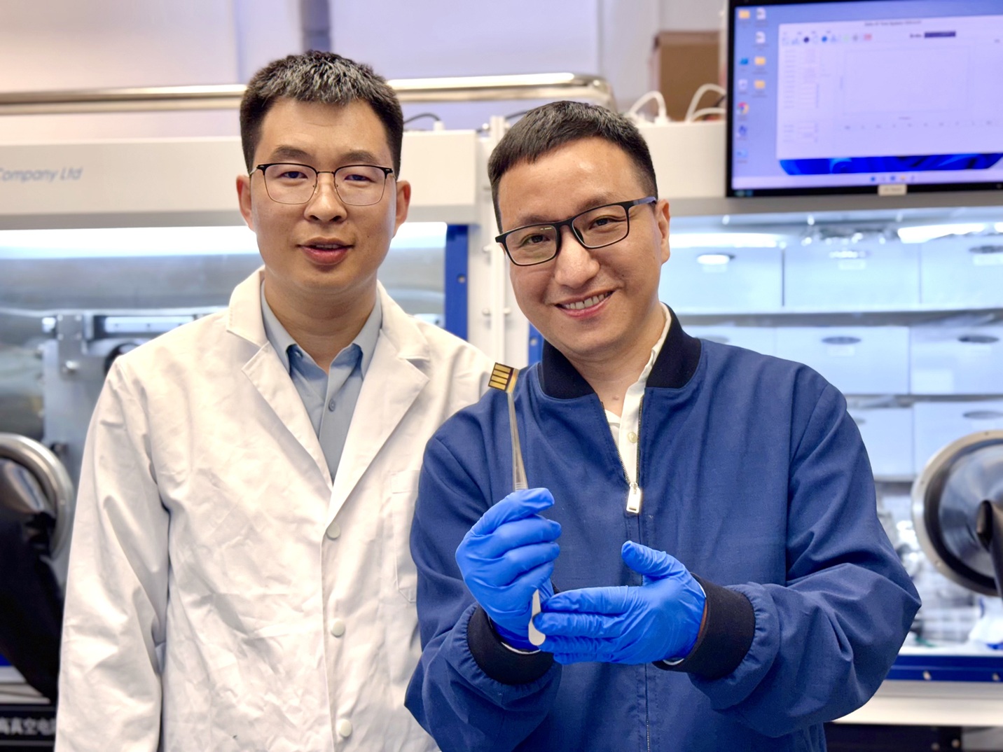 The lead corresponding author Prof. Zhou Yuanyuan and co-first author Dr. Guo Pengfei are showing a perovskite solar cell prototype made for a proof-of-concept demonstration of the novel laminate-structured interface.