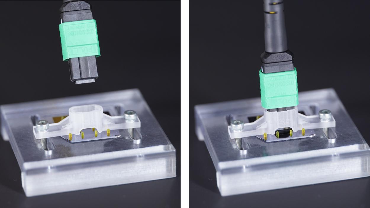 The camera image shows an array of glass fibers being plugged onto a photonic chip
